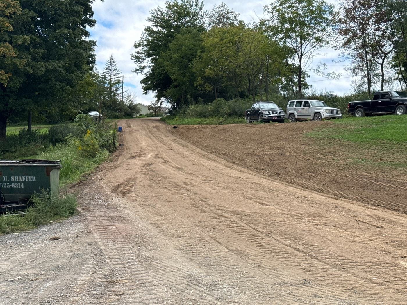 A freshly graded drive and lot beside the tree line.
