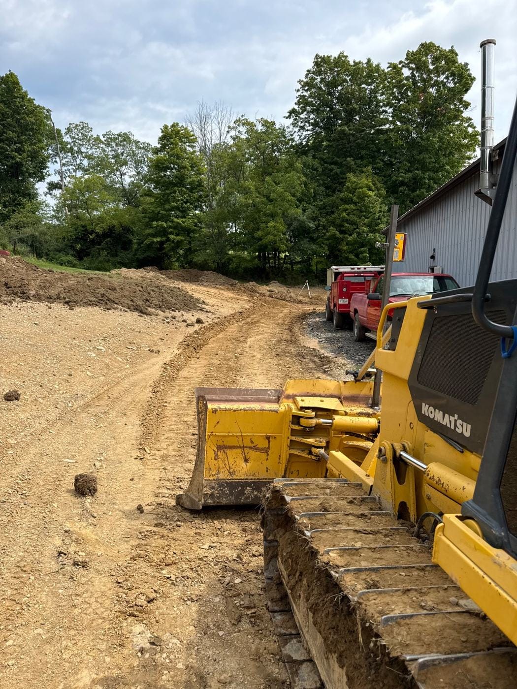 A dozer pushing dirt beside a building.