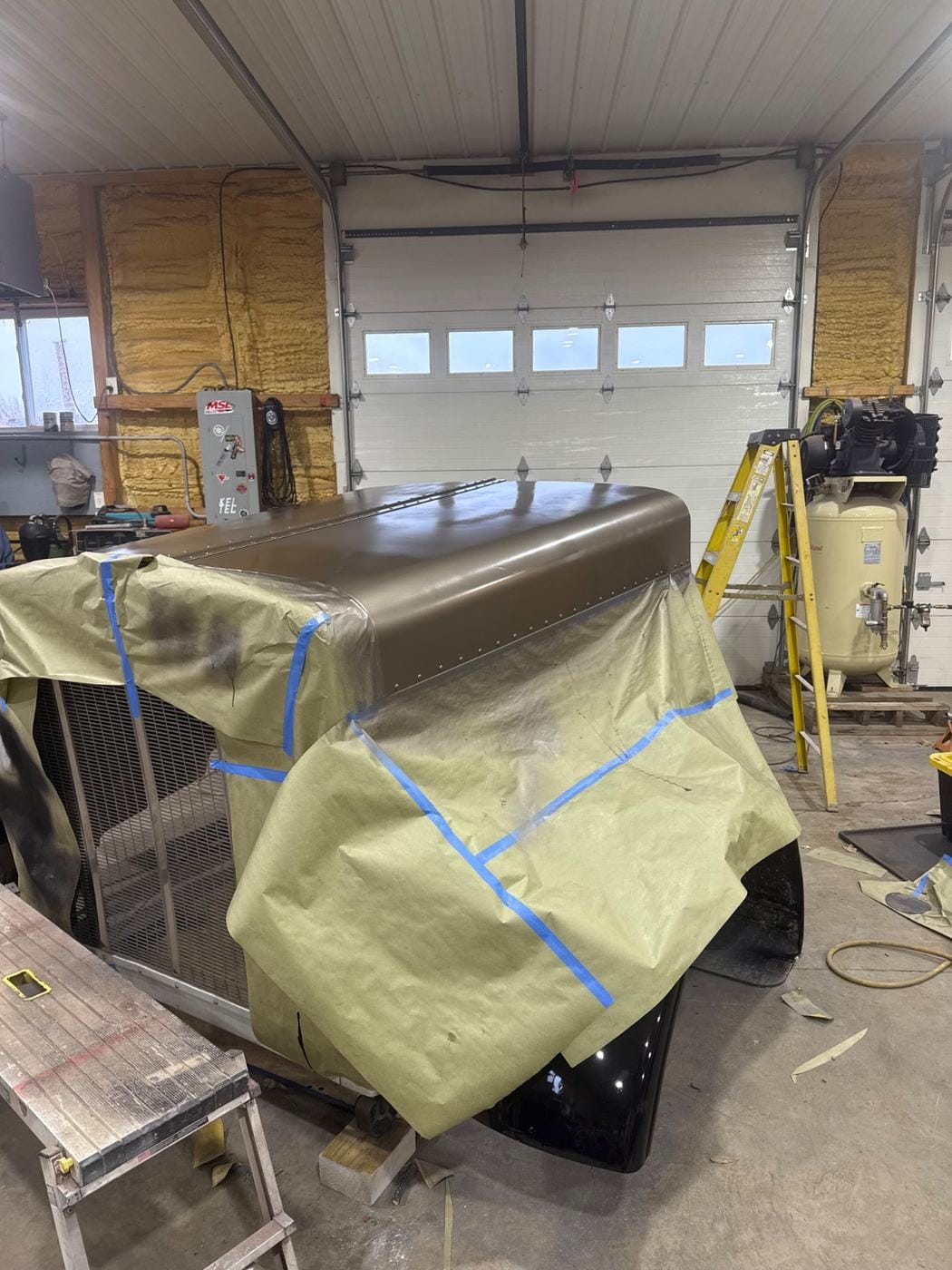 A truck hood masked off for paint in the shop.