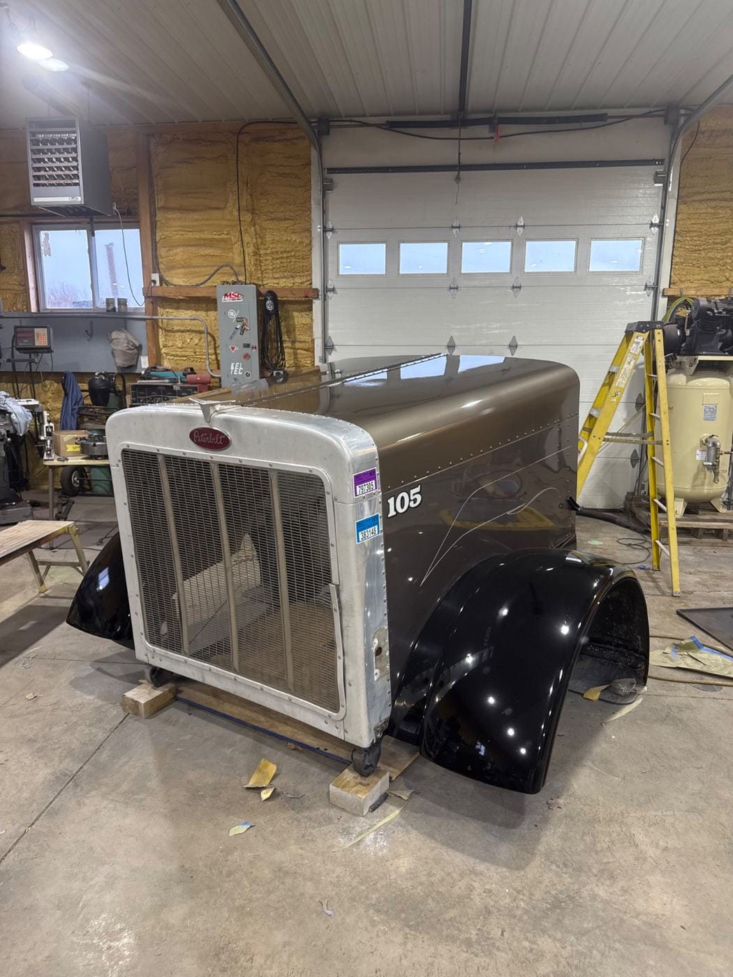 A truck hood with black fenders, set up in the shop.