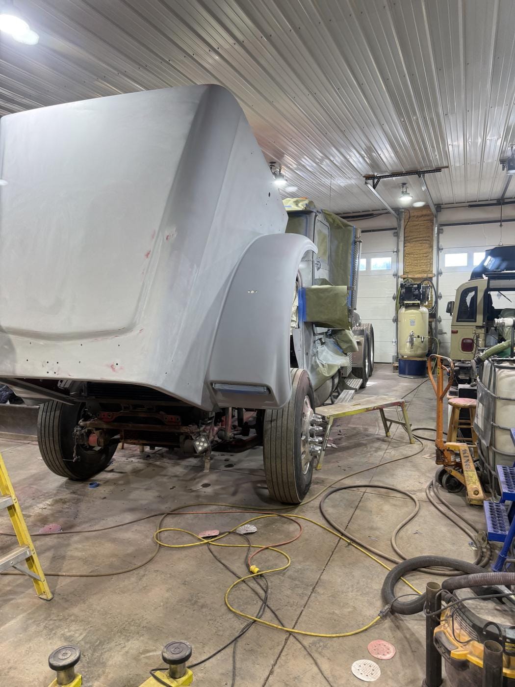 A truck hood in grey primer, set on the frame in the shop.