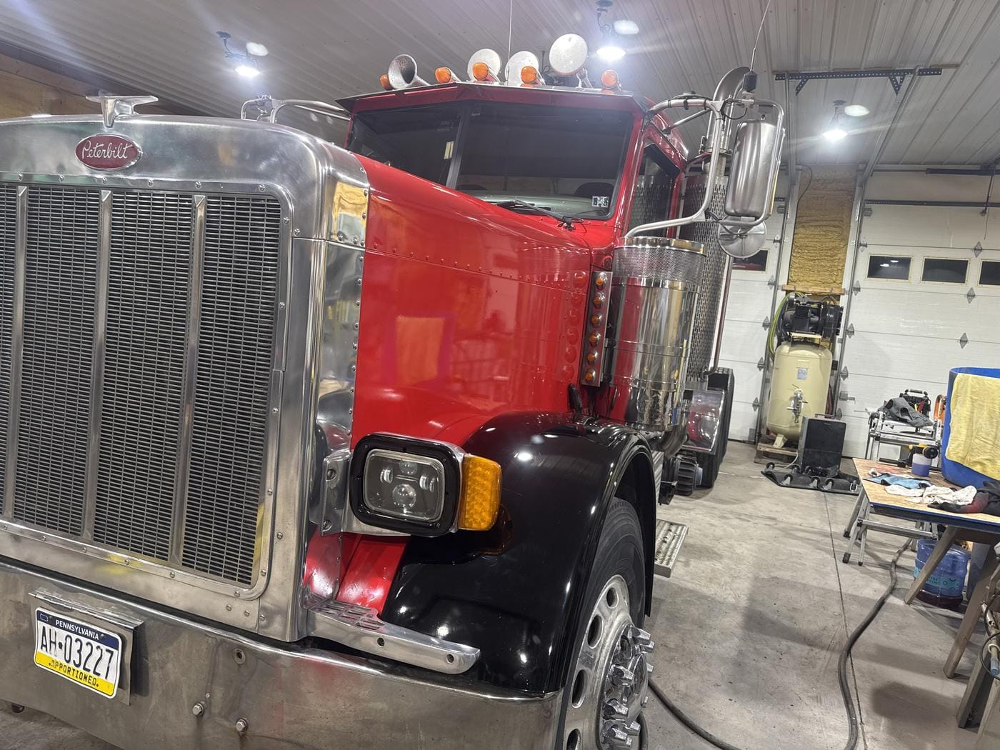 The red semi in the shop with the hood and fenders on.