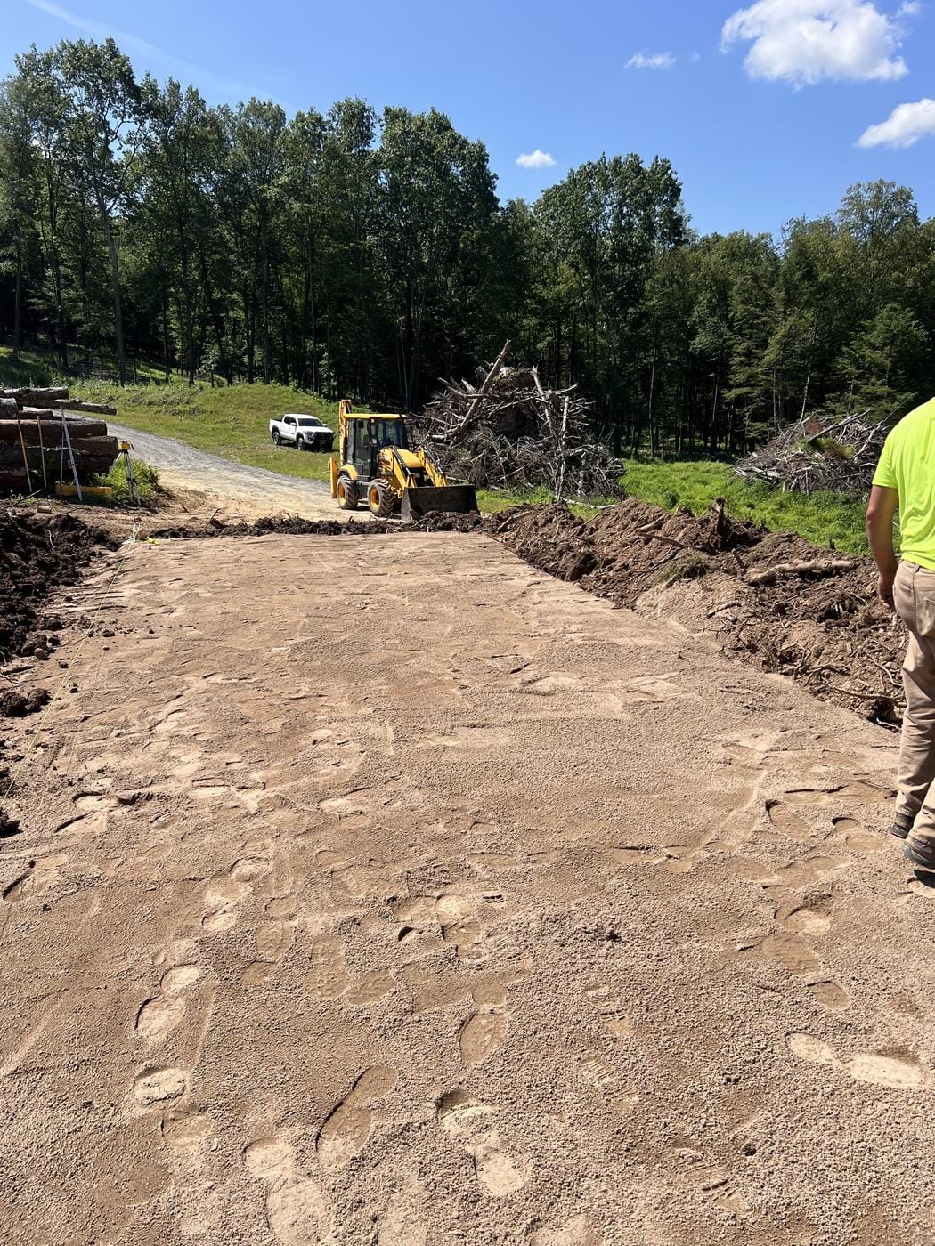 A new road bed cut in, with the backhoe and brush piles beyond.