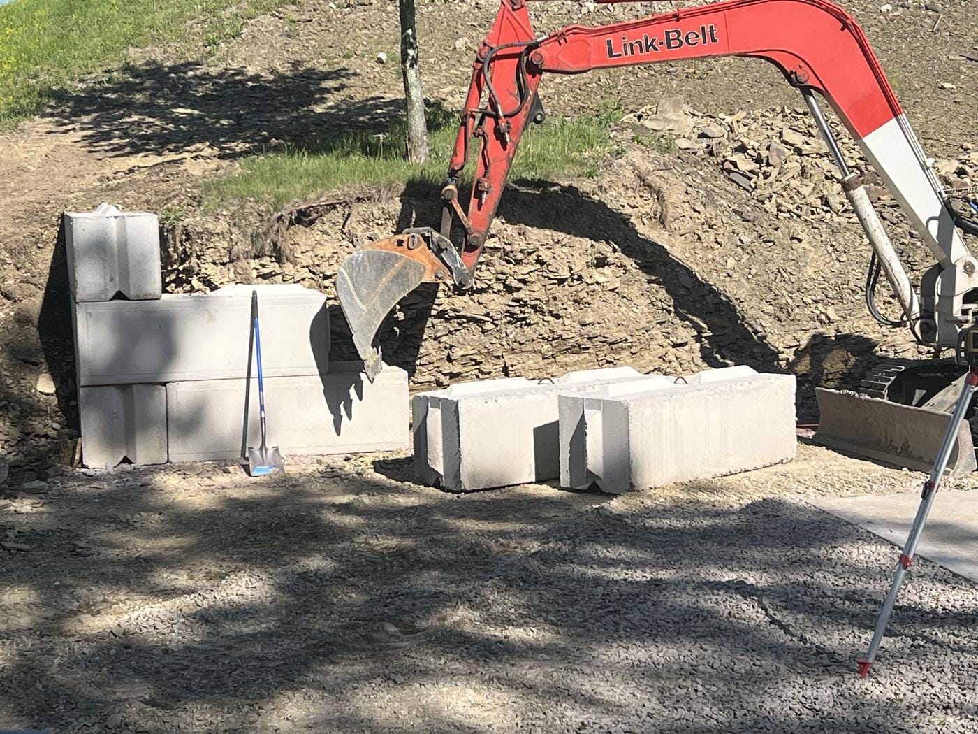 The excavator setting concrete block into the bank.