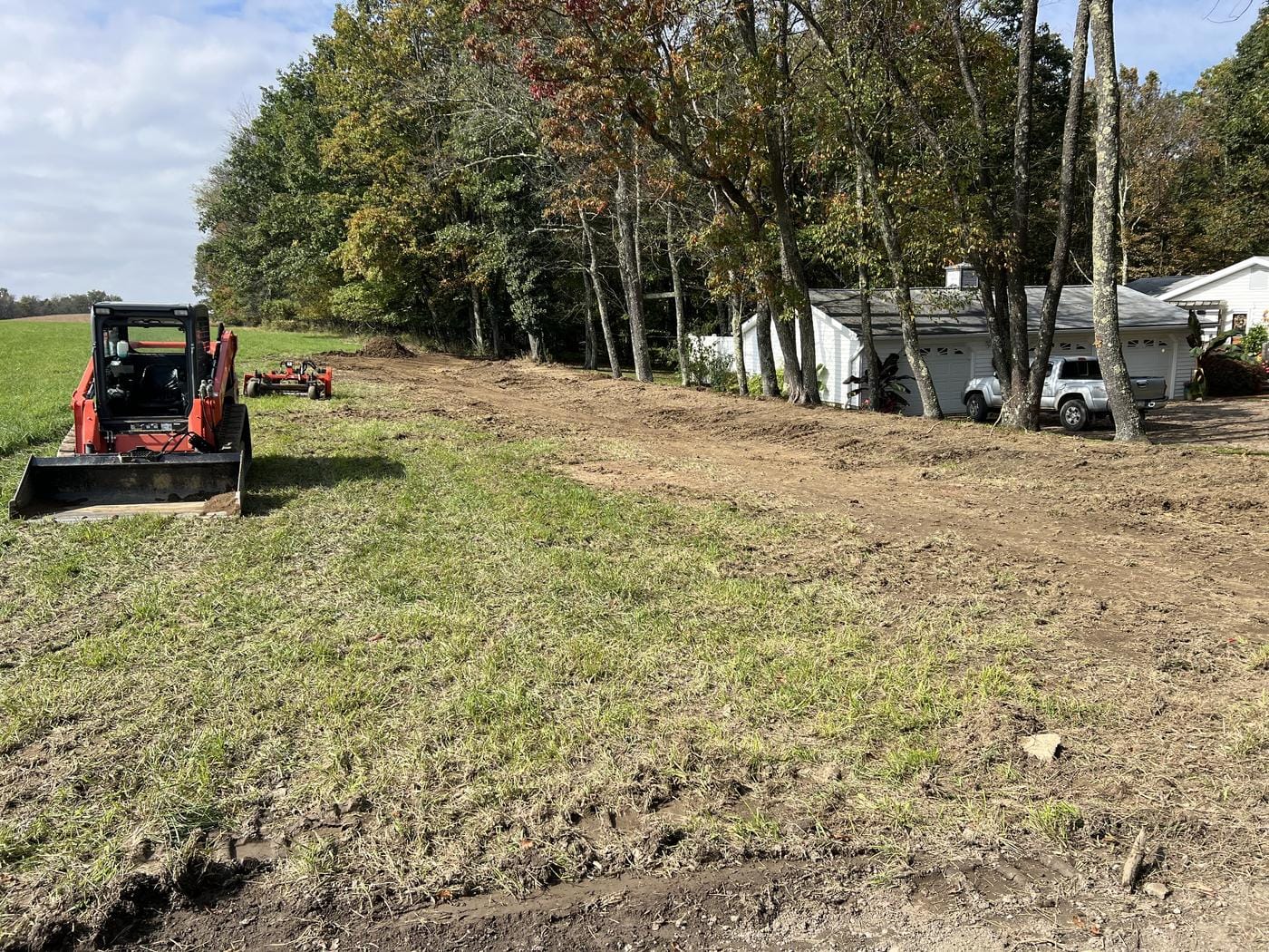 A track loader working a strip along the tree line.