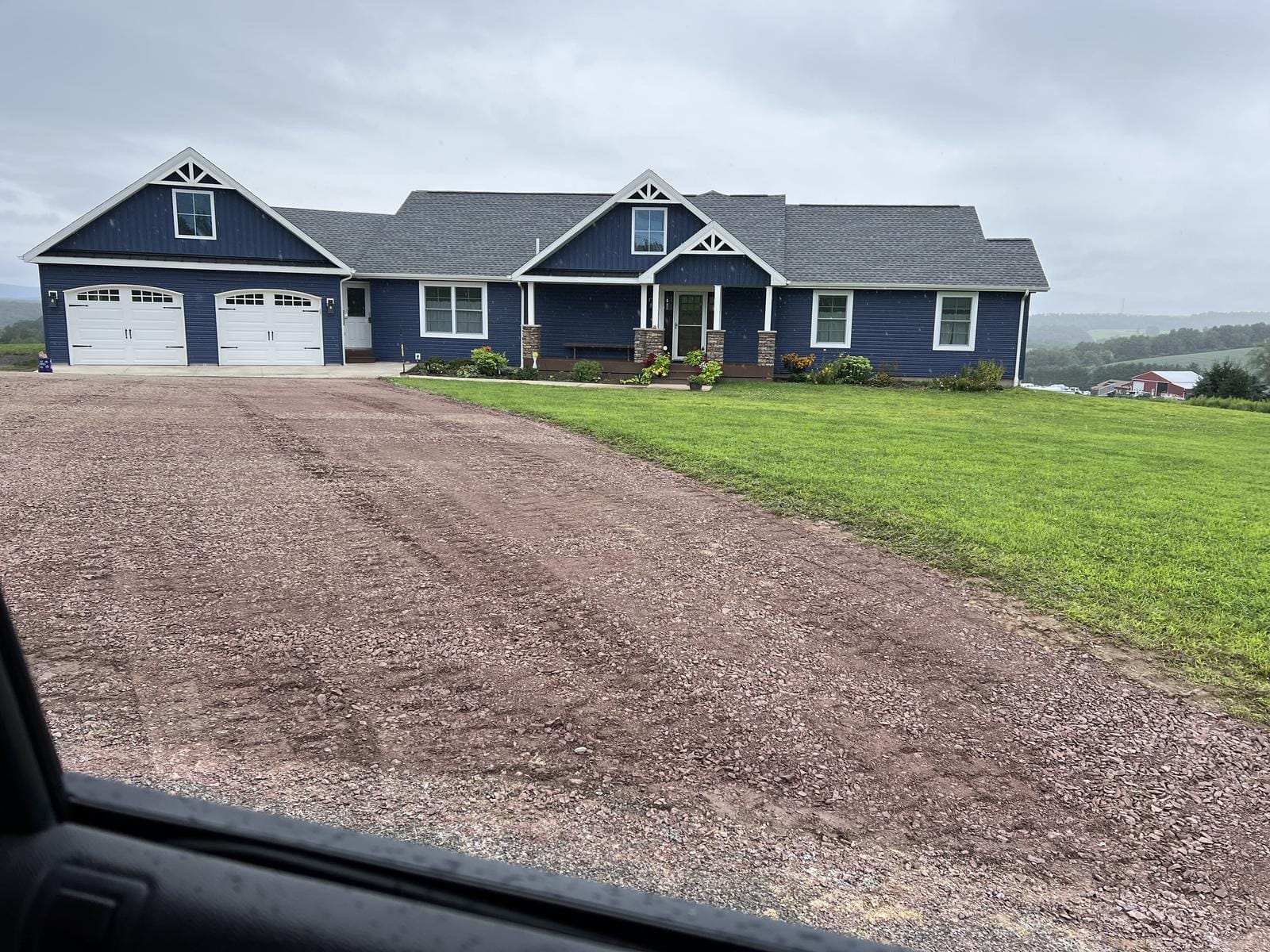 A long gravel drive up to a new house.